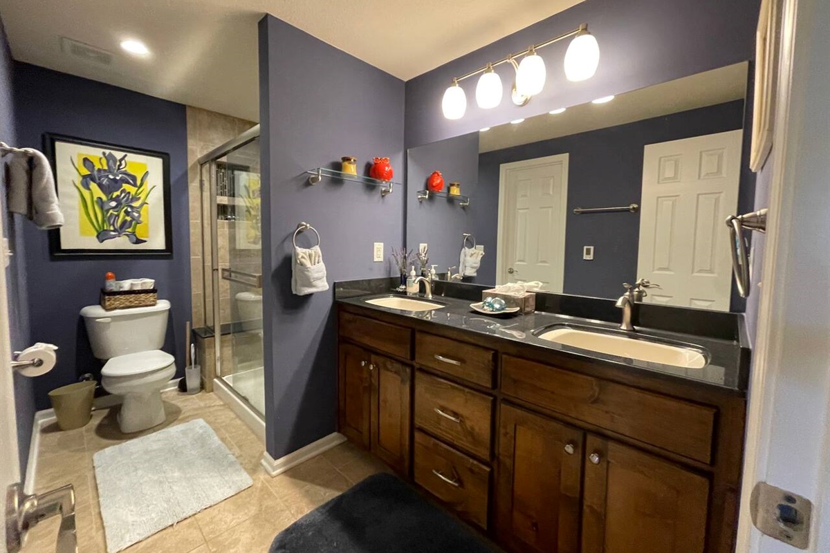 Large ceramic tiled bathroom with glass tile and natural stoned walk in shower and double sink. 