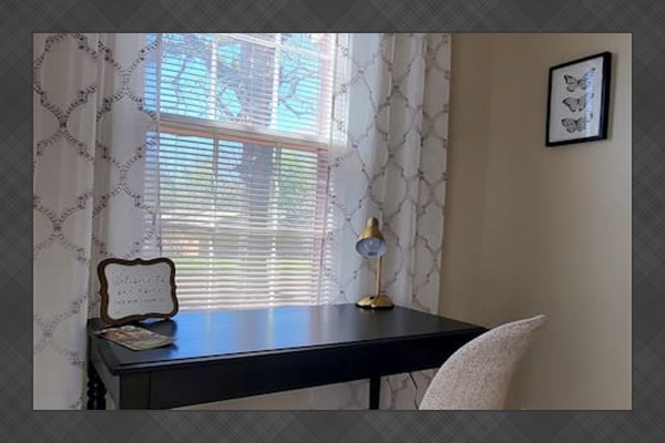 Bright and welcoming workspace with a cozy chair, desk lamp, Wi-Fi info, and natural light—perfect for remote work or planning your stay.