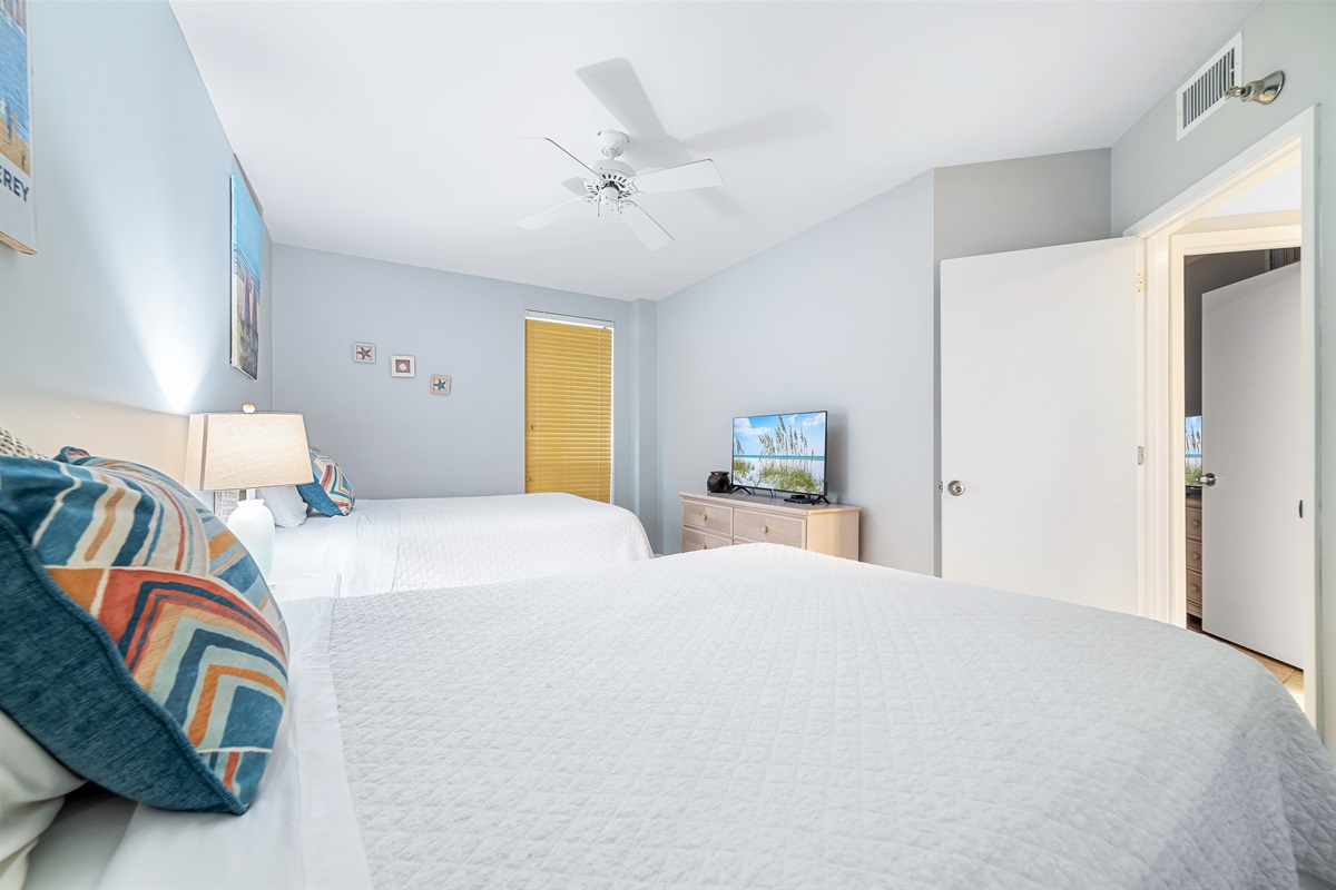 This well-appointed bedroom offers two cozy twin beds, soft lighting, and a window providing natural light and a pleasant outlook.