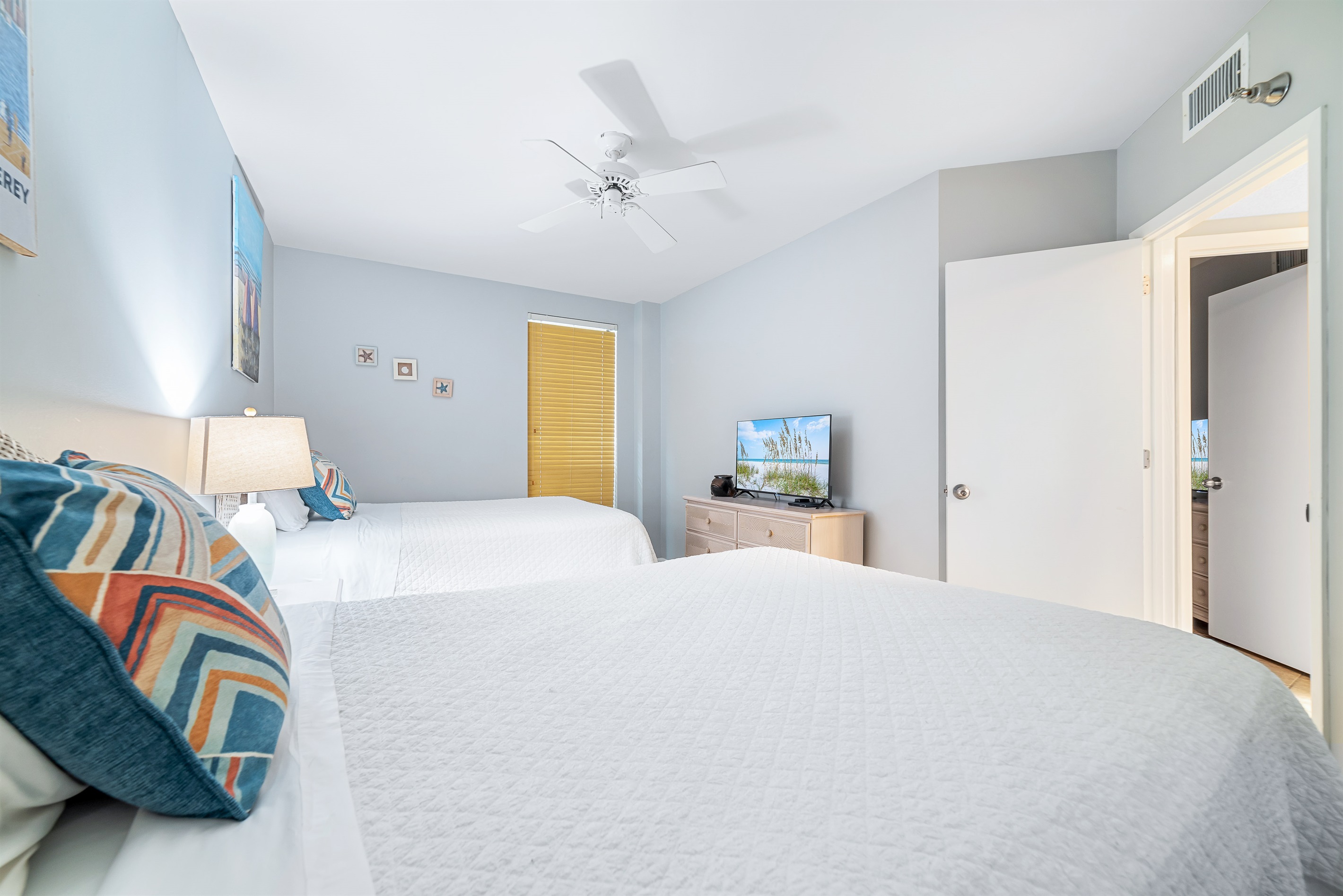 This well-appointed bedroom offers two cozy twin beds, soft lighting, and a window providing natural light and a pleasant outlook.