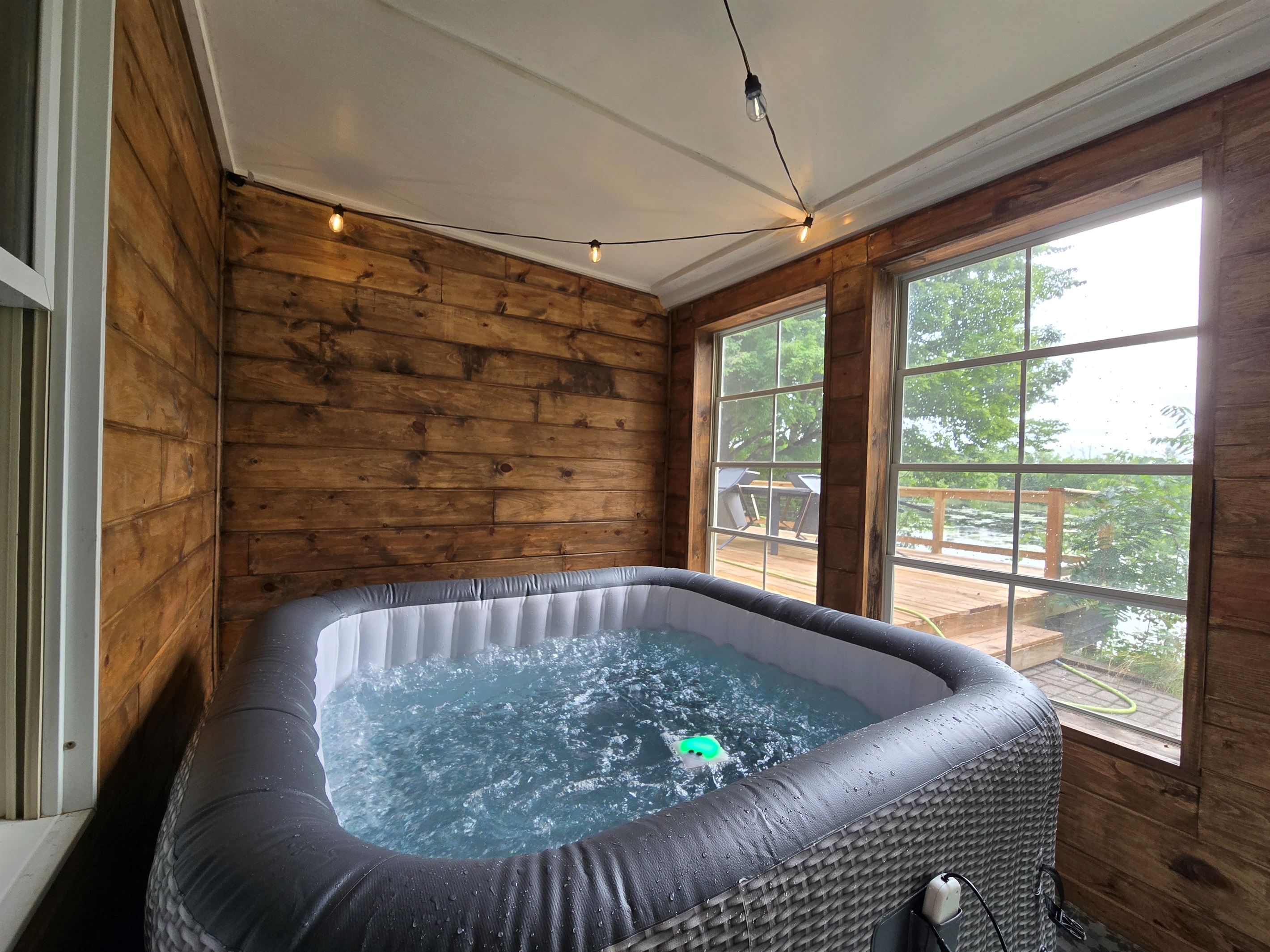 Unwind in the private hot tub overlooking the lake! 💦 Nestled in a warm cedar sunroom with glowing string lights and big windows, it’s the perfect place to relax after a day of trails, water fun, or s’mores by the firepit.