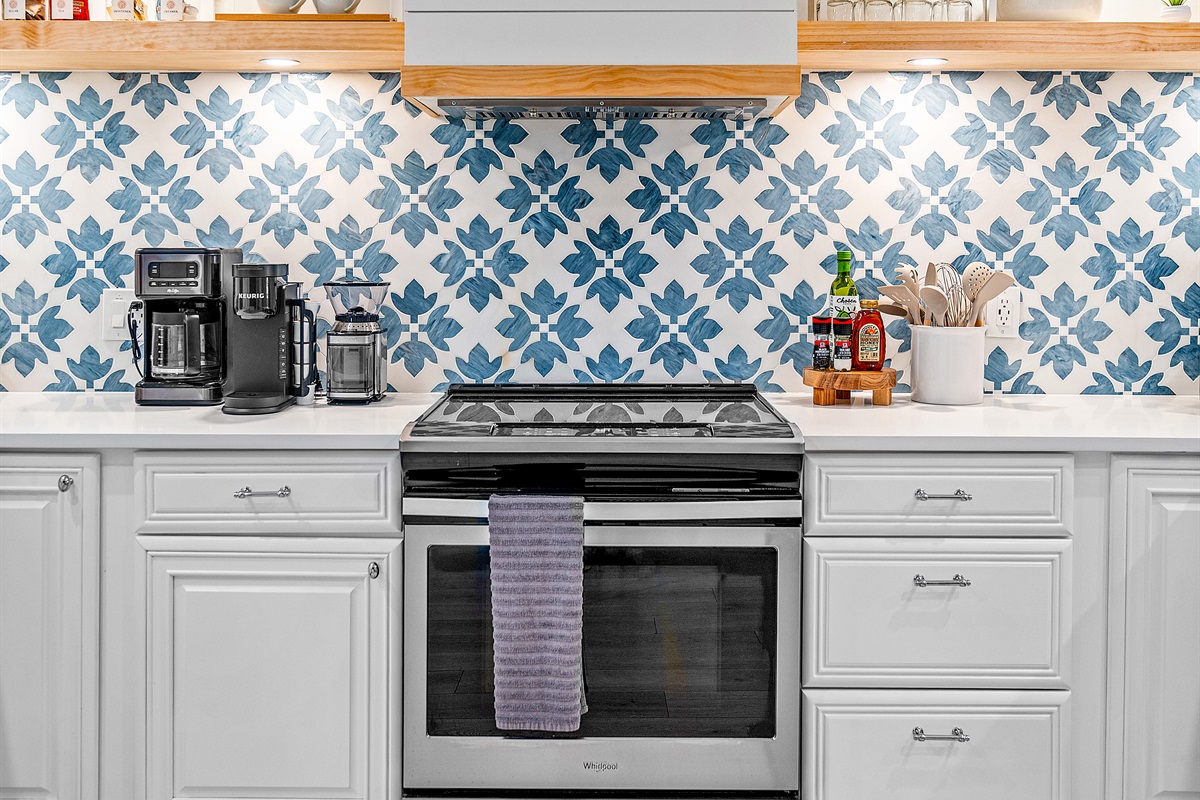 Cook with style! Our modern stove/oven is set against a beautiful tiled backsplash, ready for your gourmet meals. We include pots, pans, and basic cooking essentials.