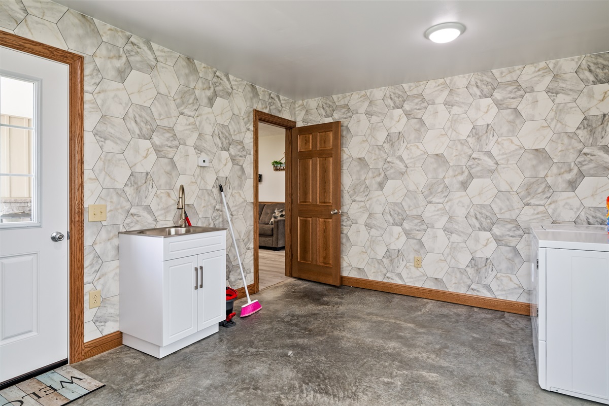 Functional mudroom/laundry combo with deep sink, storage, and durable finishes perfect for any stay.