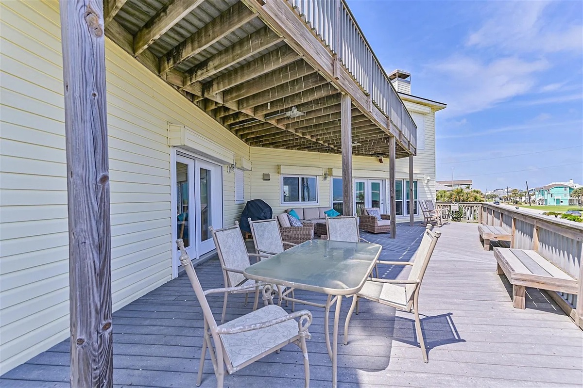 Covered deck with dining, lounge chairs, and propane grill