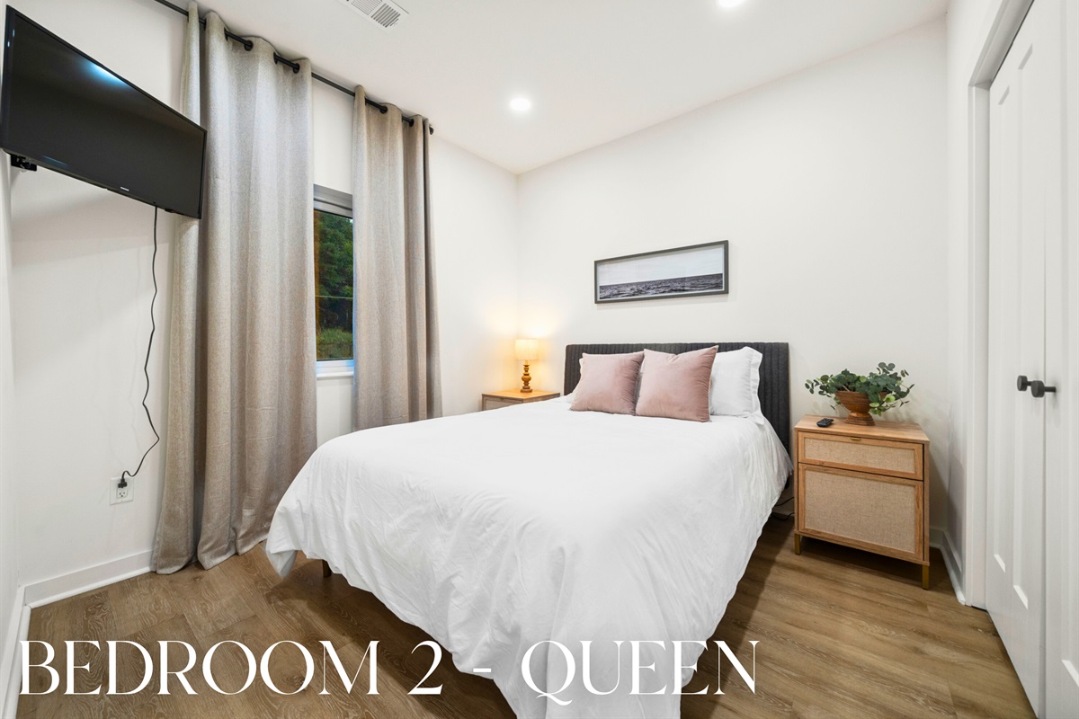 Guest bedroom with queen bed and warm natural tones.
