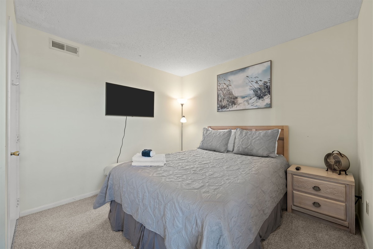 Comfortable bedroom with a wall-mounted TV, soft neutral tones, and practical furnishings designed for an easy, restful stay