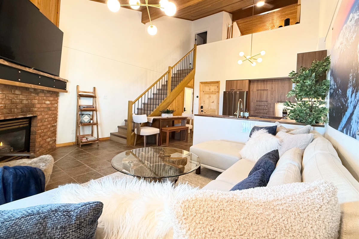Mountain Retreat Comfort: This living area connects seamlessly to the kitchen and loft, offering a welcoming atmosphere and a cozy gas fireplace for your mountain getaway.