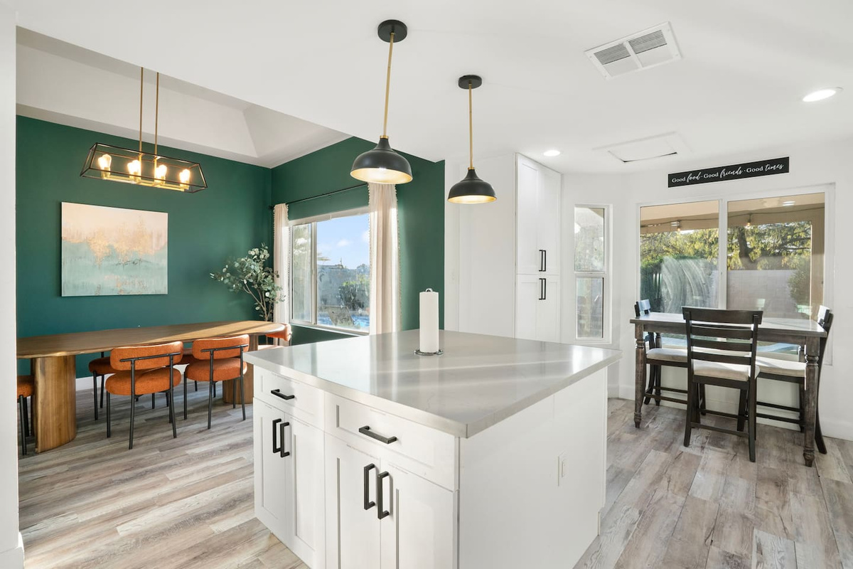 Multi-zone room with forest green accent wall, chef's island, workspace, and scenic window views.