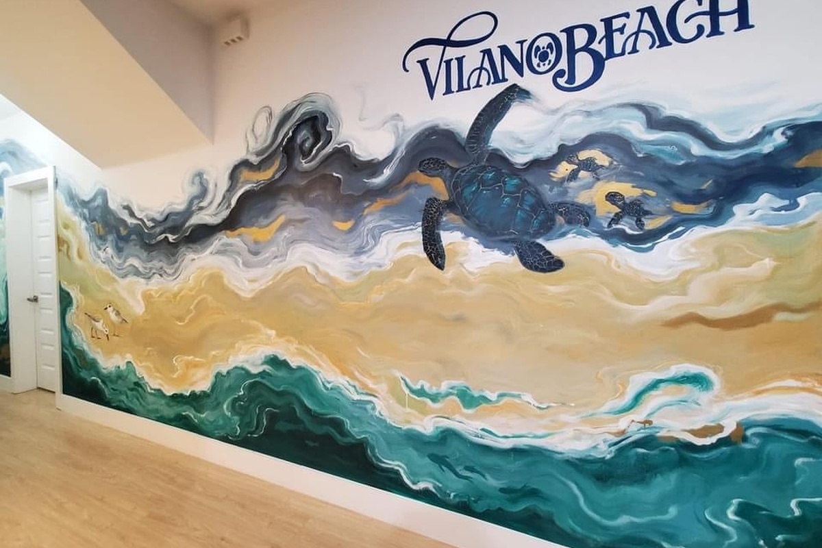 An artist painted this wall by hand - turtles, sandpipers, and the Atlantic rolling in beneath the words Vilano Beach. It is the sort of detail that tells you the people who built this house love the place.