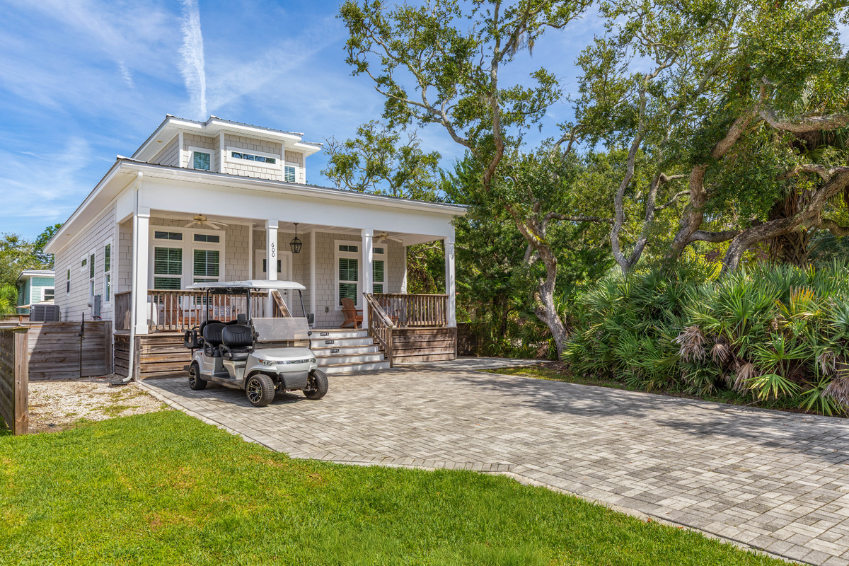 Live oaks lean over the yard and palmettos hold the property line, so the house feels tucked away rather than squeezed in. Room to park, room to unload, and a patch of lawn for whoever thought to bring a ball.