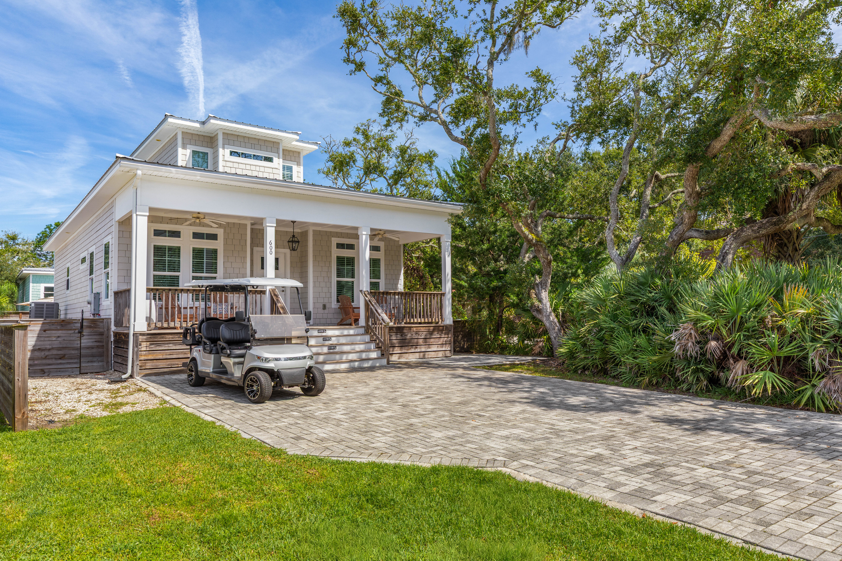 Live oaks lean over the yard and palmettos hold the property line, so the house feels tucked away rather than squeezed in. Room to park, room to unload, and a patch of lawn for whoever thought to bring a ball.