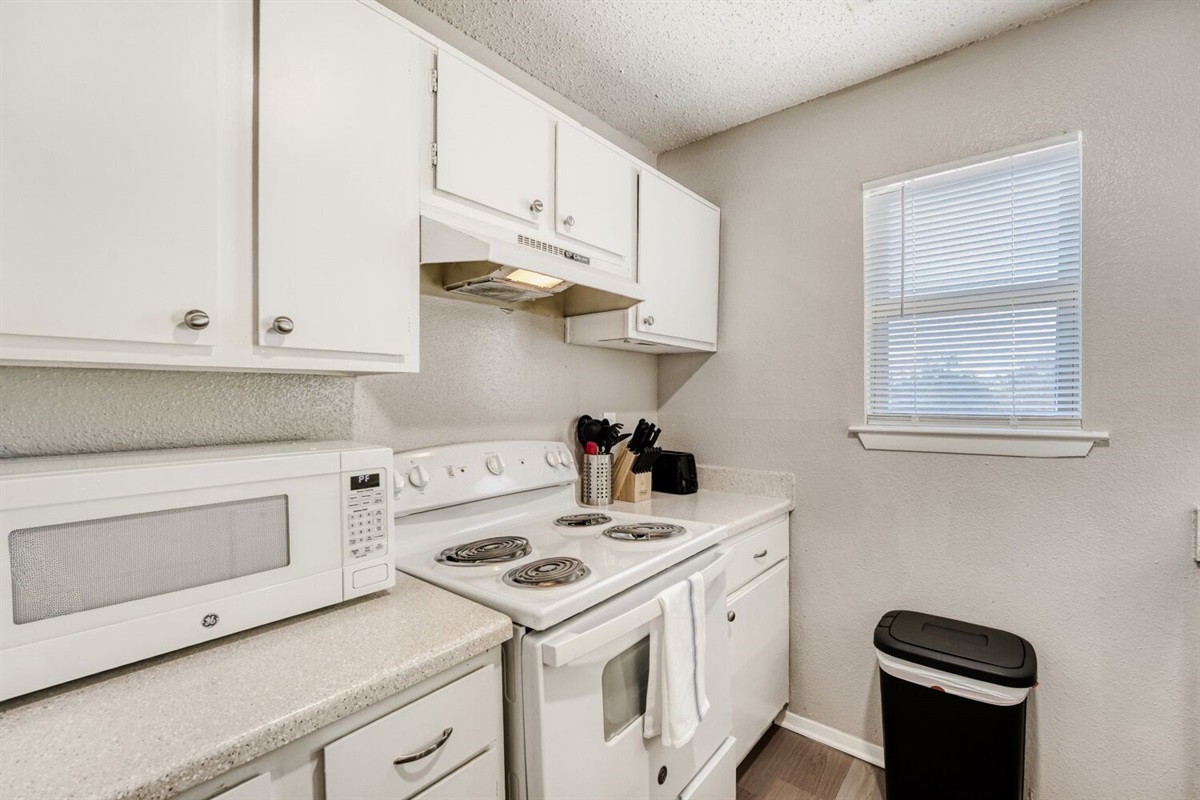 Compact white kitchen with modern appliances and bright natural light.