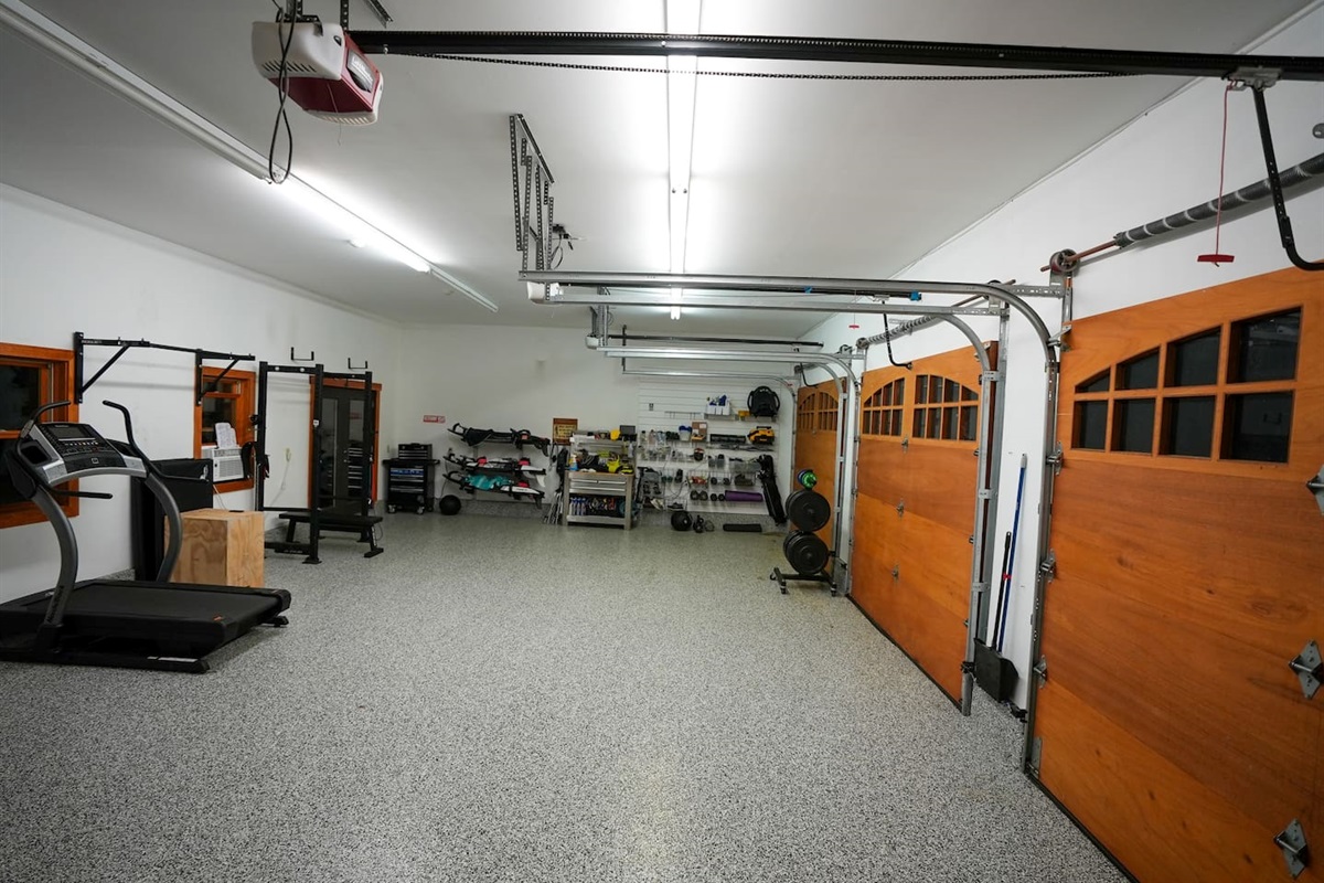 Garage with epoxy floor, treadmill, pull up bar, air conditioning and more.