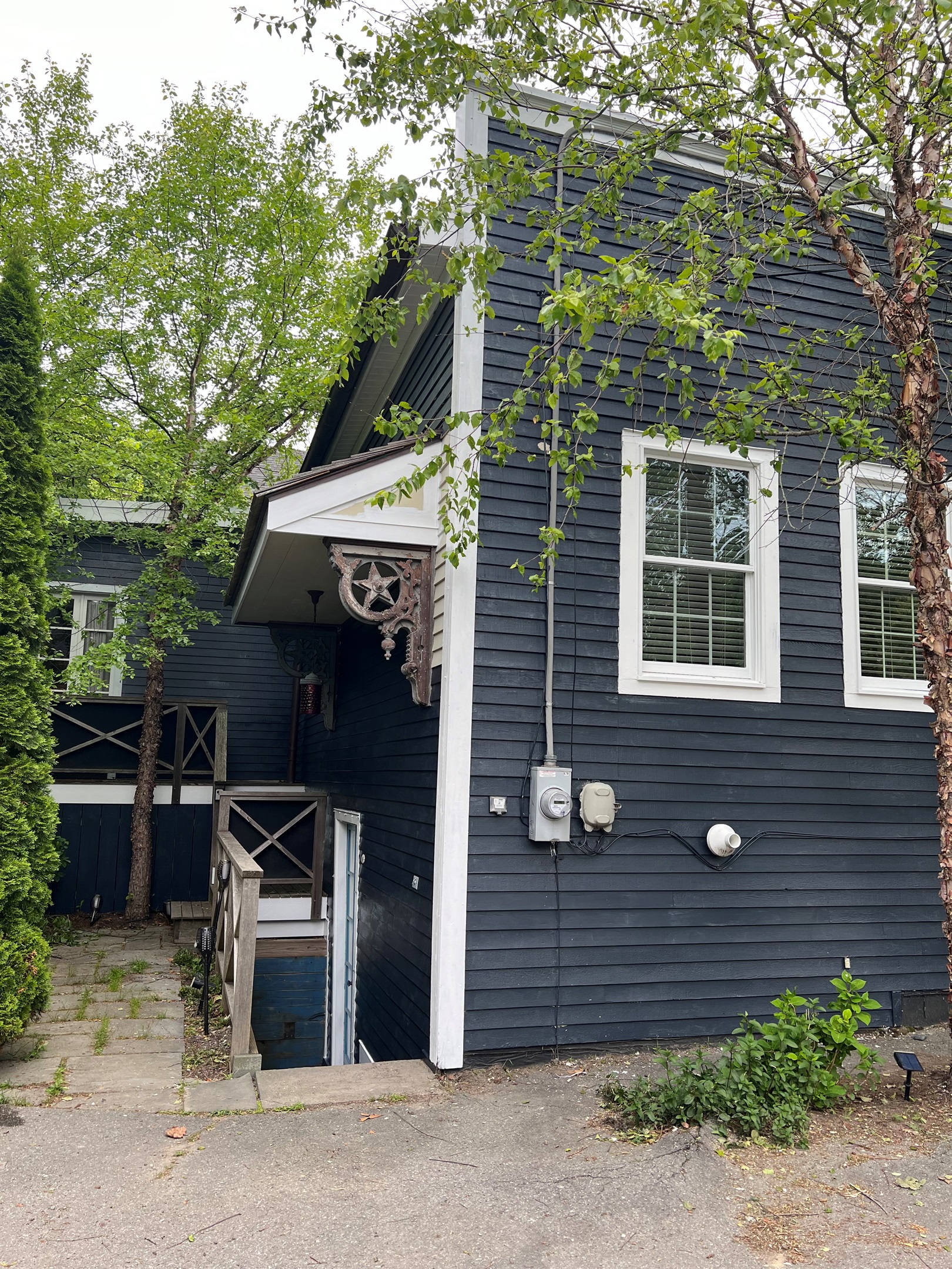 Private Outdoor Oasis: Dedicated patio with grill and seating nestled behind mature cedars. This space connects the upper balcony deck off the primary King wing to the direct-access stairs leading to our ship-inspired "Below Deck" dining area.