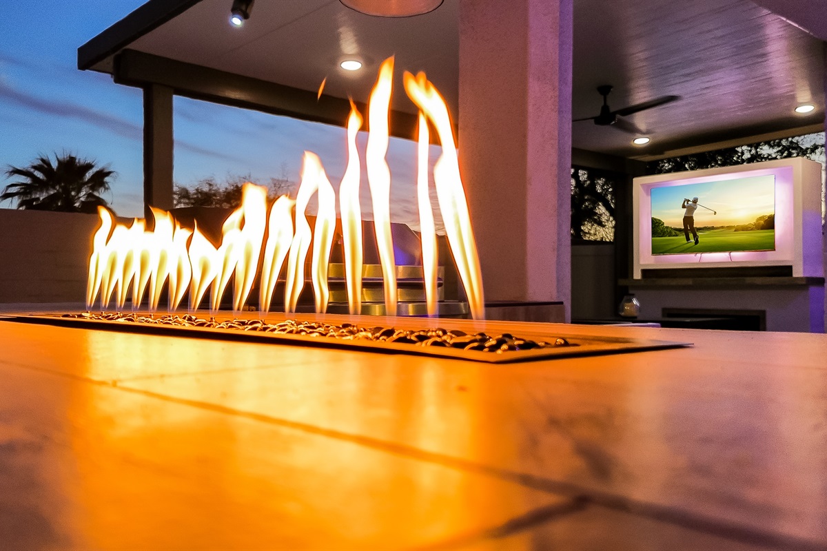 Outdoor island with natural gas BBQ, pizza oven, and tabletop fire feature.