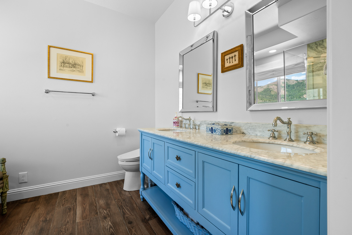 This beautifully appointed bathroom features a striking blue double vanity, elegant countertops, polished fixtures, and generous space for guests to prepare for the day with ease.