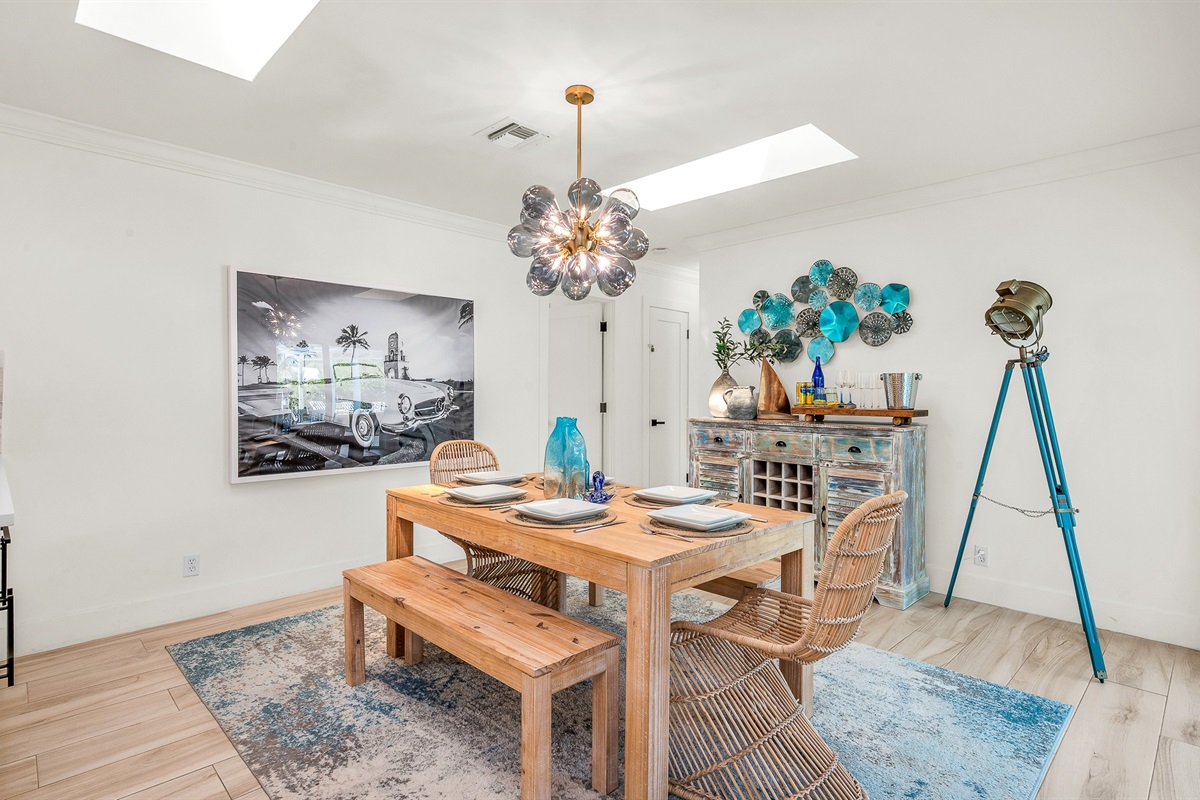 Gather around the rustic wood dining table with seating for six, accented by chic rattan chairs and a statement chandelier. Surrounded by natural light and stylish coastal décor, it’s the perfect space for enjoying meals or entertaining in style.