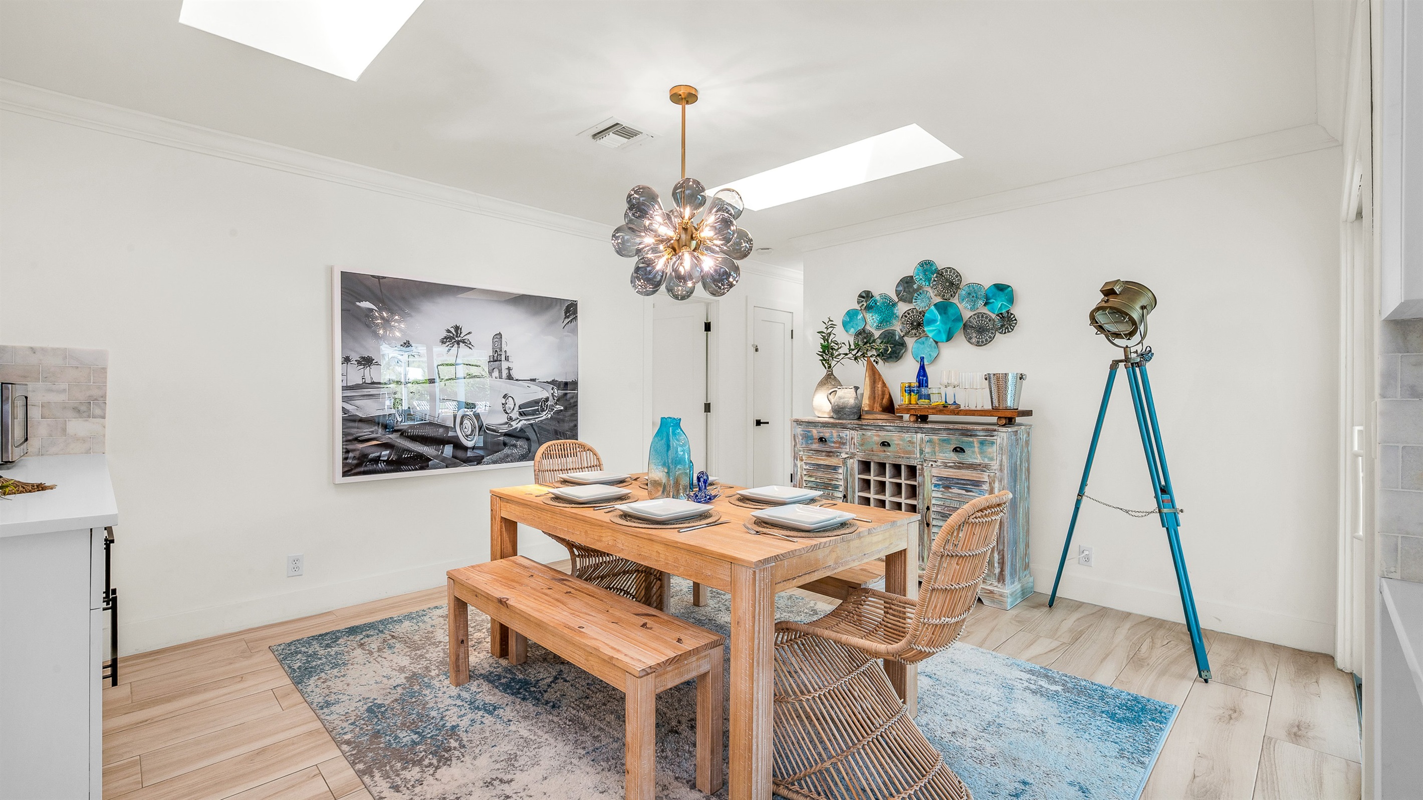 Gather around the rustic wood dining table with seating for six, accented by chic rattan chairs and a statement chandelier. Surrounded by natural light and stylish coastal décor, it’s the perfect space for enjoying meals or entertaining in style.