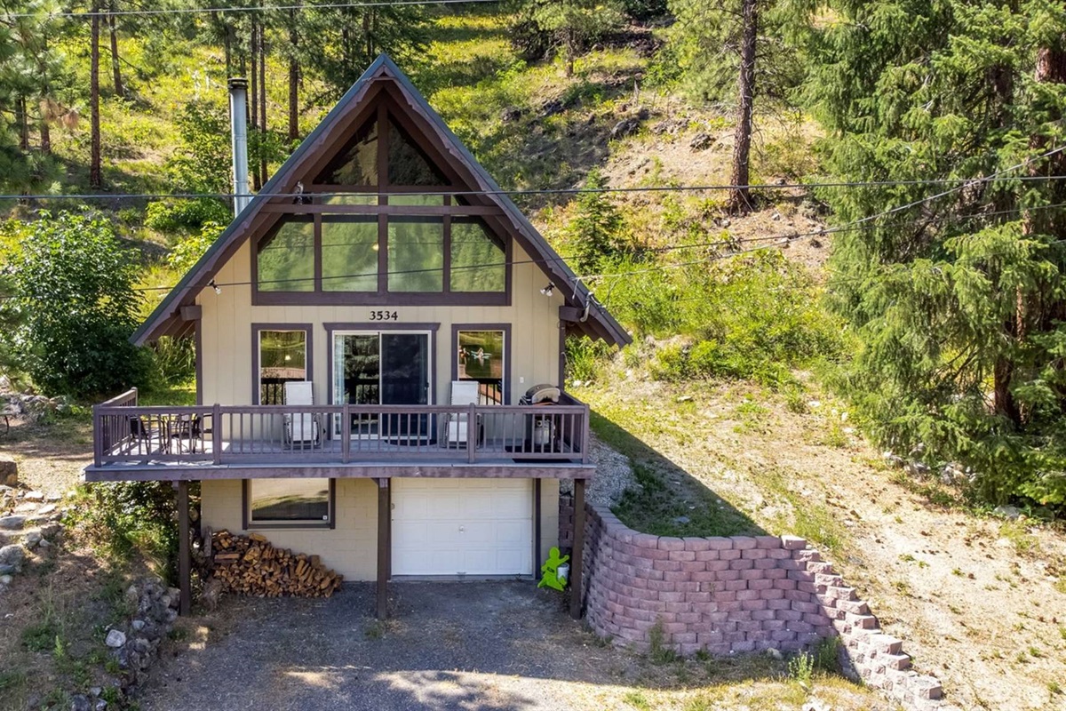 Classic A-frame architecture surrounded by forested hills.