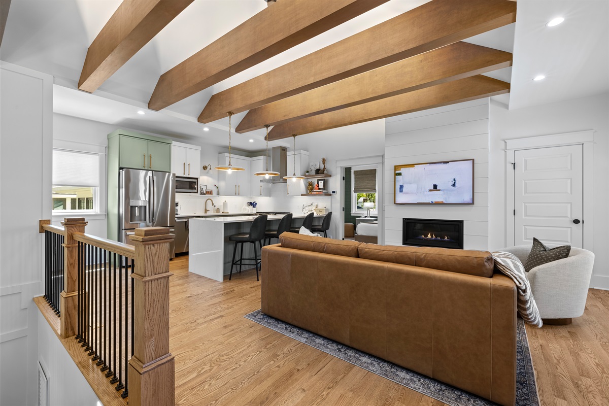 Bright open-concept living space with vaulted ceilings and exposed beams.
