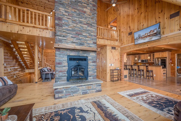 Living Room with stunning 2+ story fireplace. Living Room flows into the kitchen and additional seating in the entryway.