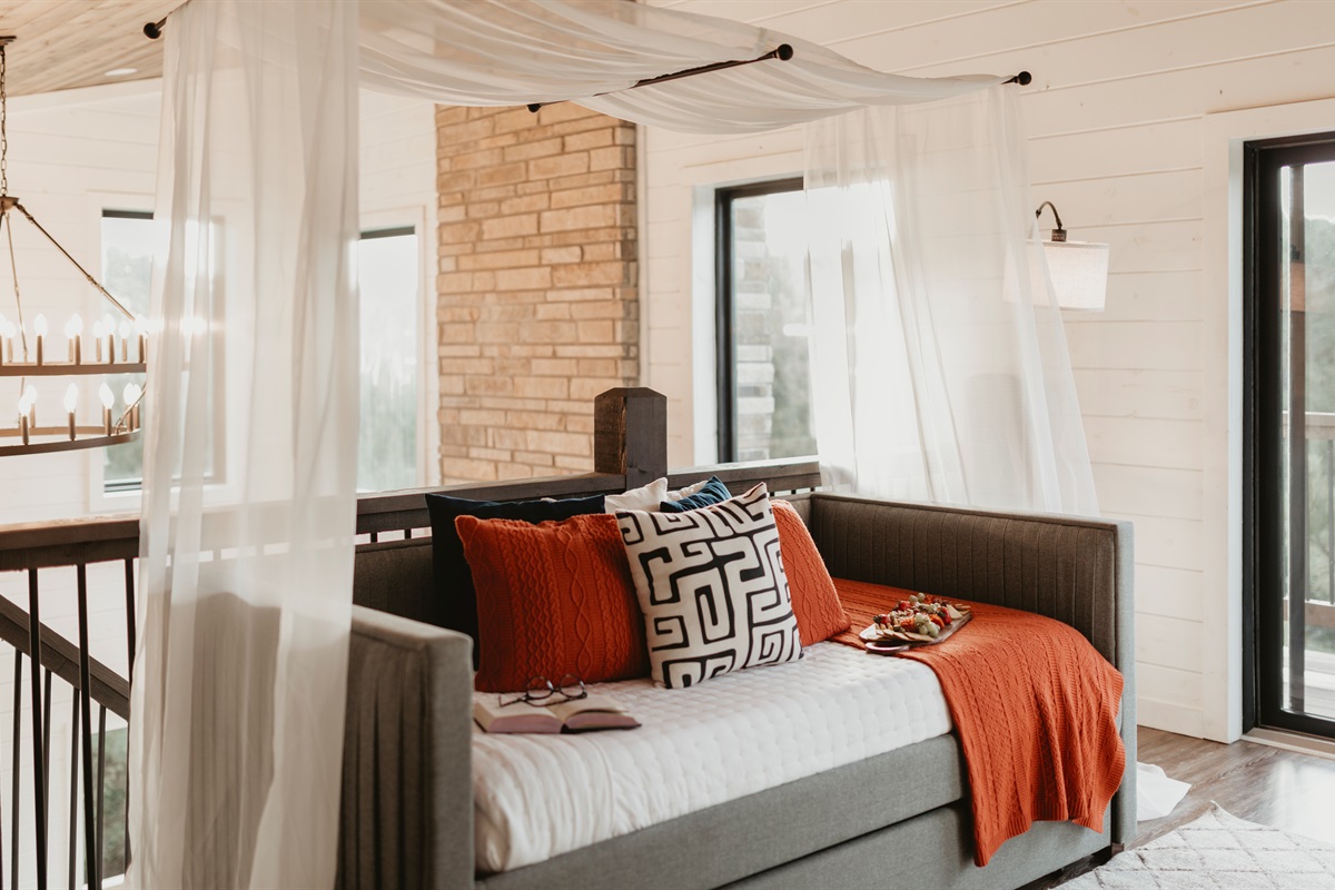 Tucked under a canopy of soft sheers, this peaceful daybed is the perfect spot to unwind, nap, or curl up with a good book.
