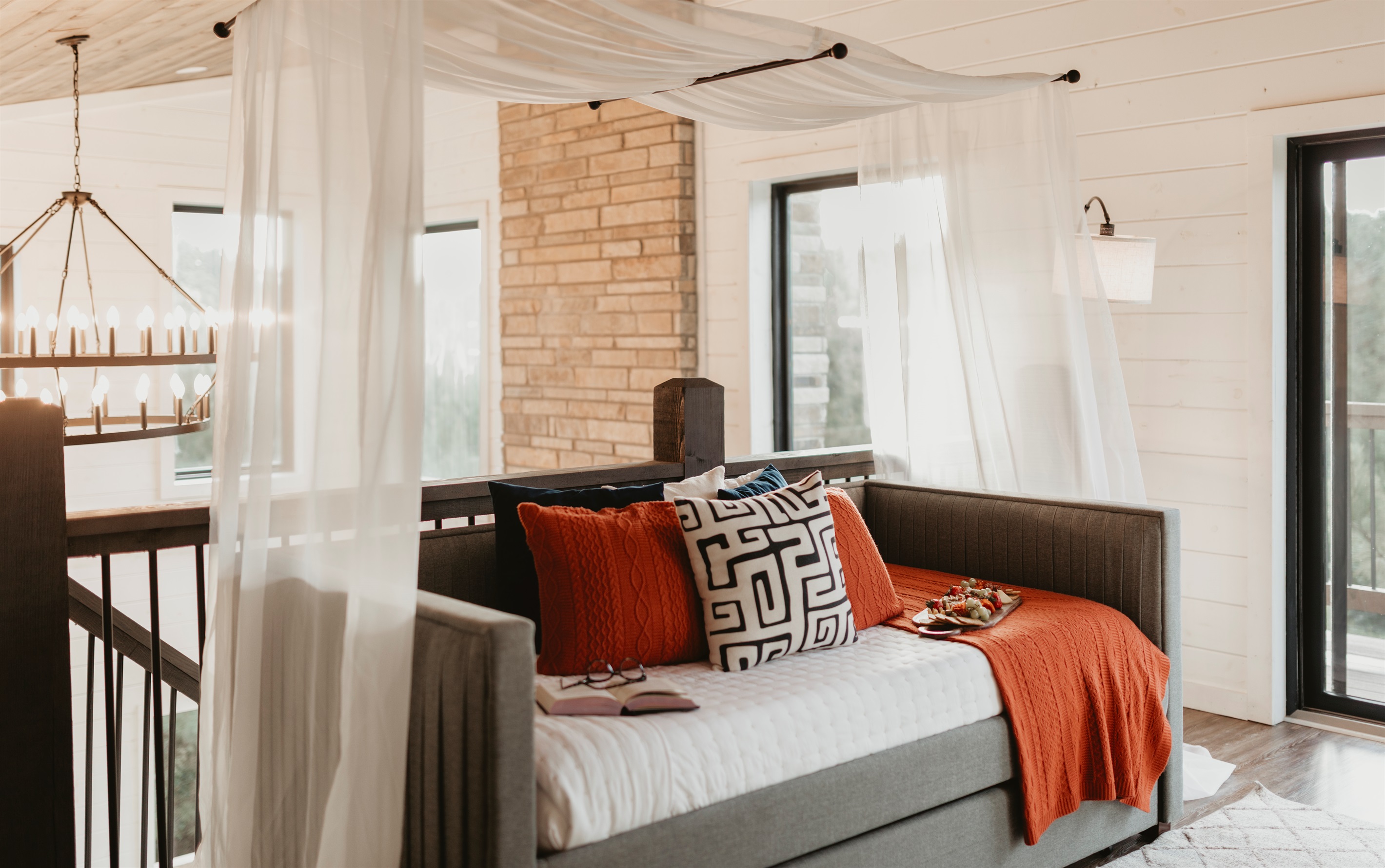Tucked under a canopy of soft sheers, this peaceful daybed is the perfect spot to unwind, nap, or curl up with a good book.