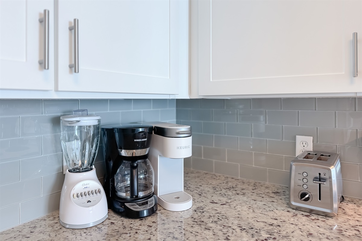 Enjoy your morning brew with both a traditional coffee pot and a single-serve machine, complemented by essential countertop appliances in this well-equipped kitchen.