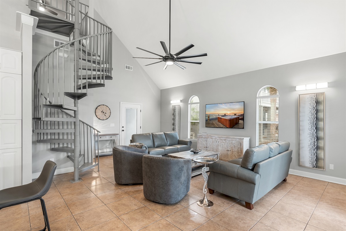 Spacious living room with plush leather seating and spiral staircase feature