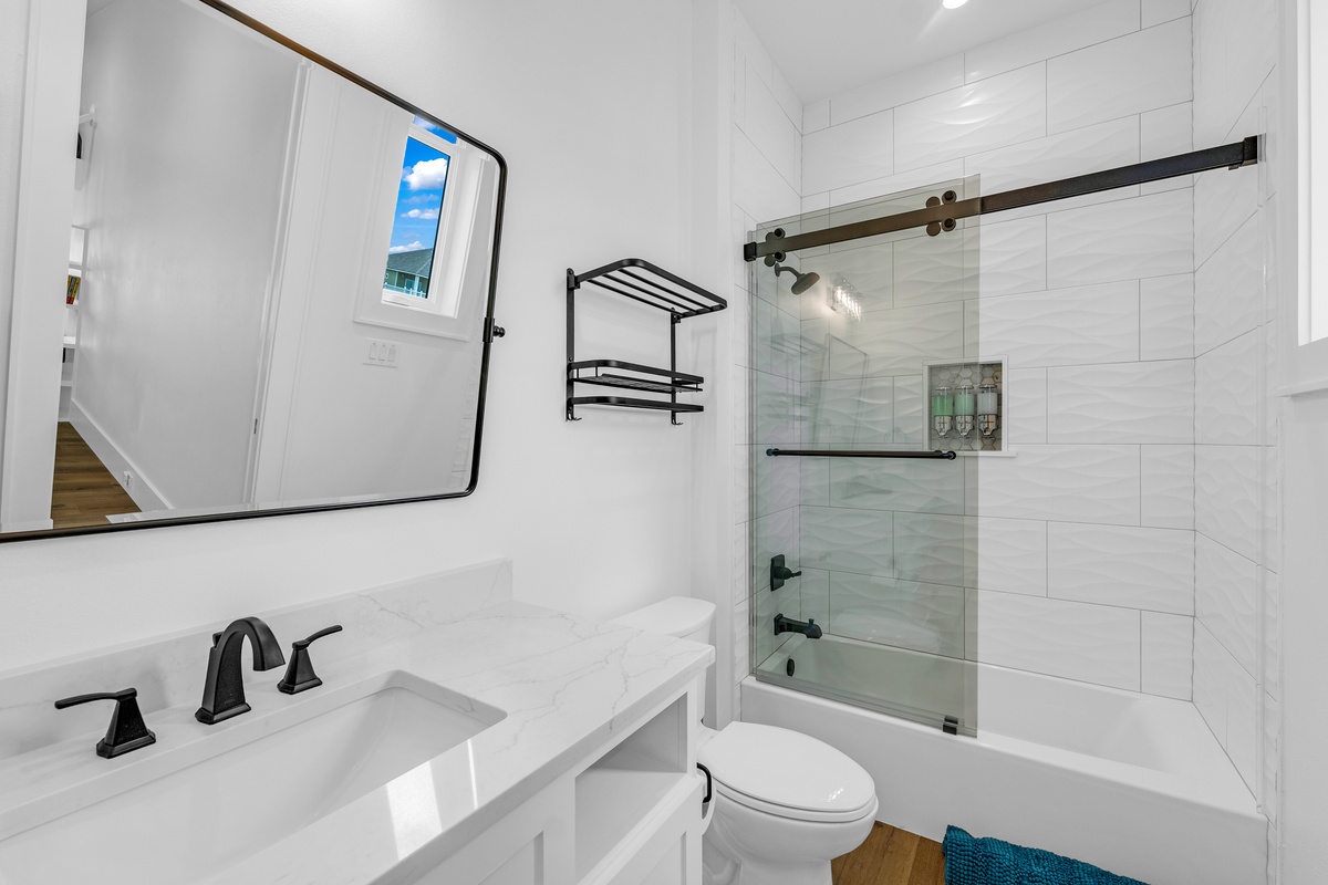 Cair Paravel: A glass-enclosed tub/shower combo with wave-textured tile keeps this bath equally suited to a quick rinse or a long soak.