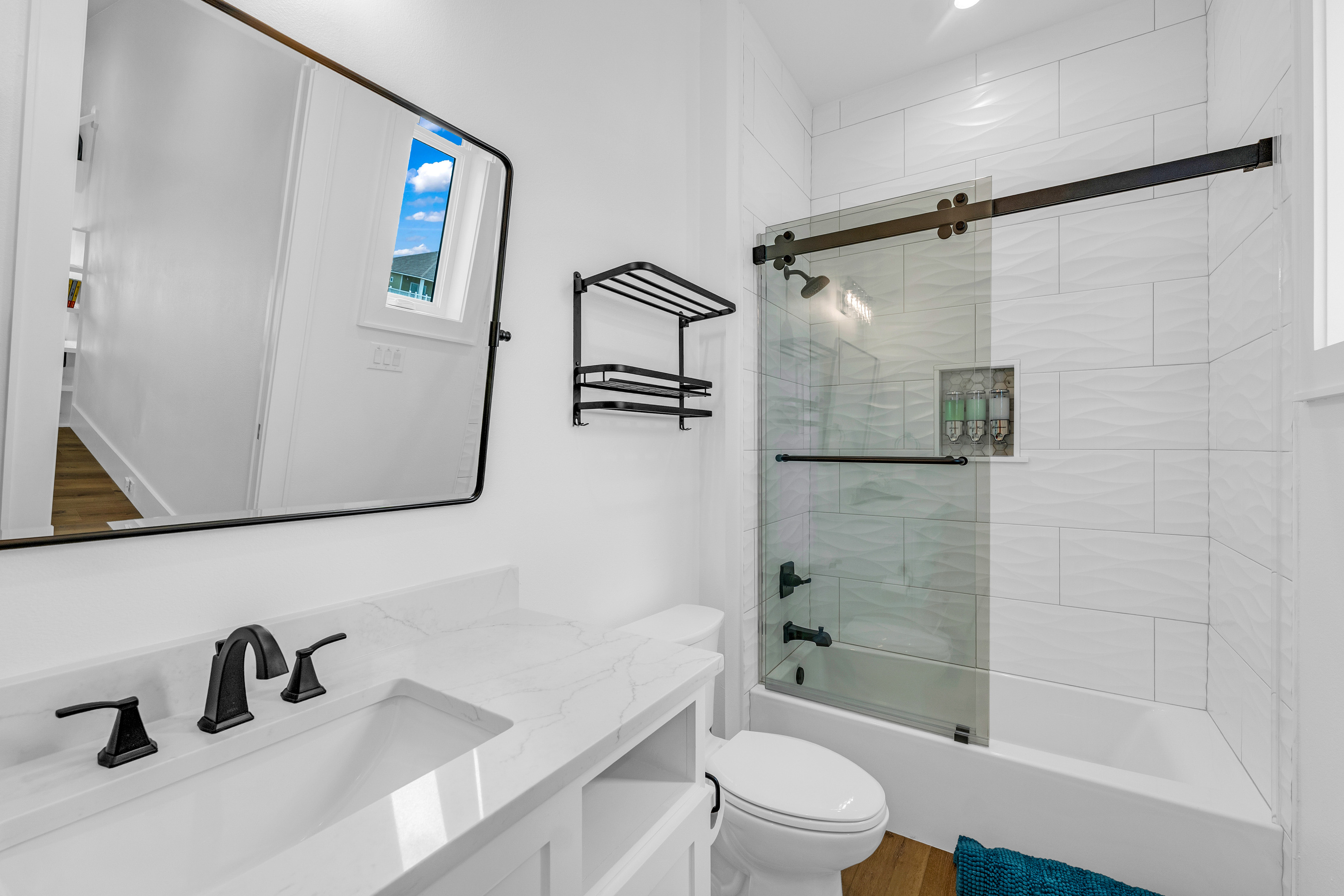 Cair Paravel: A glass-enclosed tub/shower combo with wave-textured tile keeps this bath equally suited to a quick rinse or a long soak.