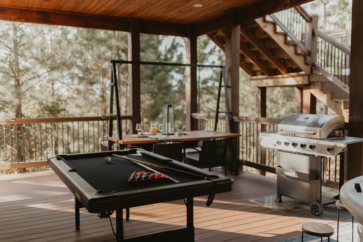 Grill, dine, and play under the pines—this covered deck brings it all together with a pool table, dining space, and BBQ grill. Perfect for game nights, cookouts, and laid-back hangs surrounded by forest views.