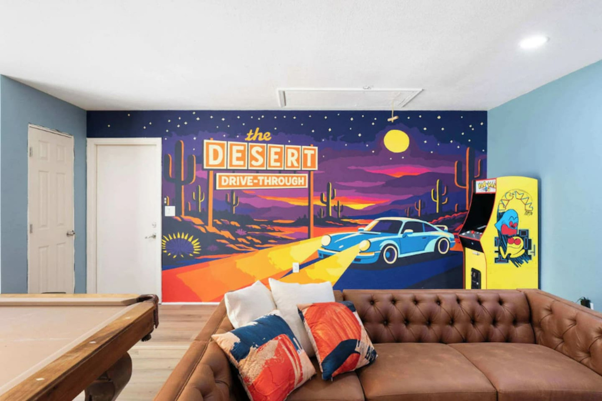 Retro game room with iconic Desert Drive-Through mural, leather seating, pool table, and arcade—nostalgic fun space for all ages.