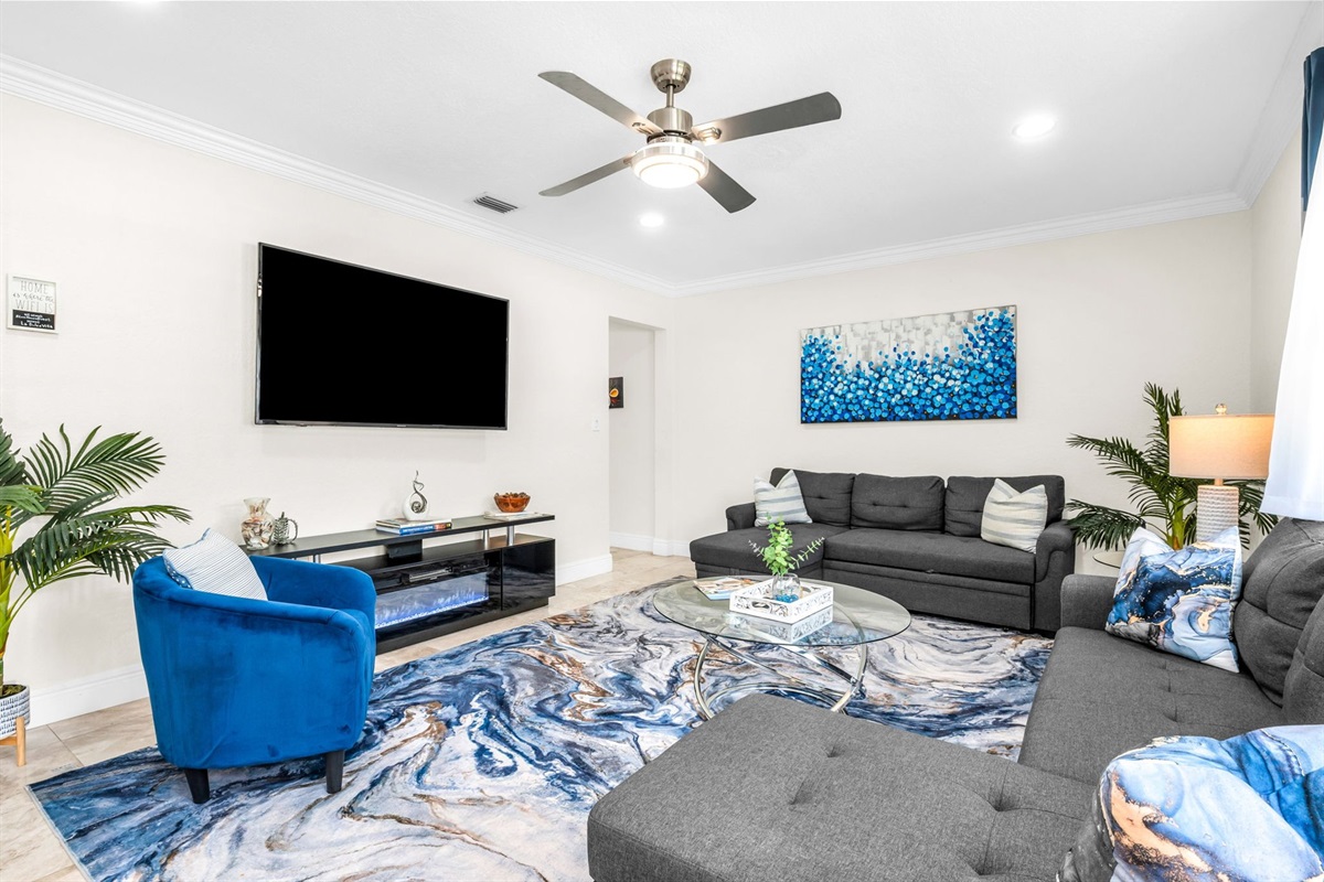 Large family-friendly living room with two queen pull-out sofas, flat-screen smart TV, and stylish coastal décor—great for groups needing extra sleeping options.