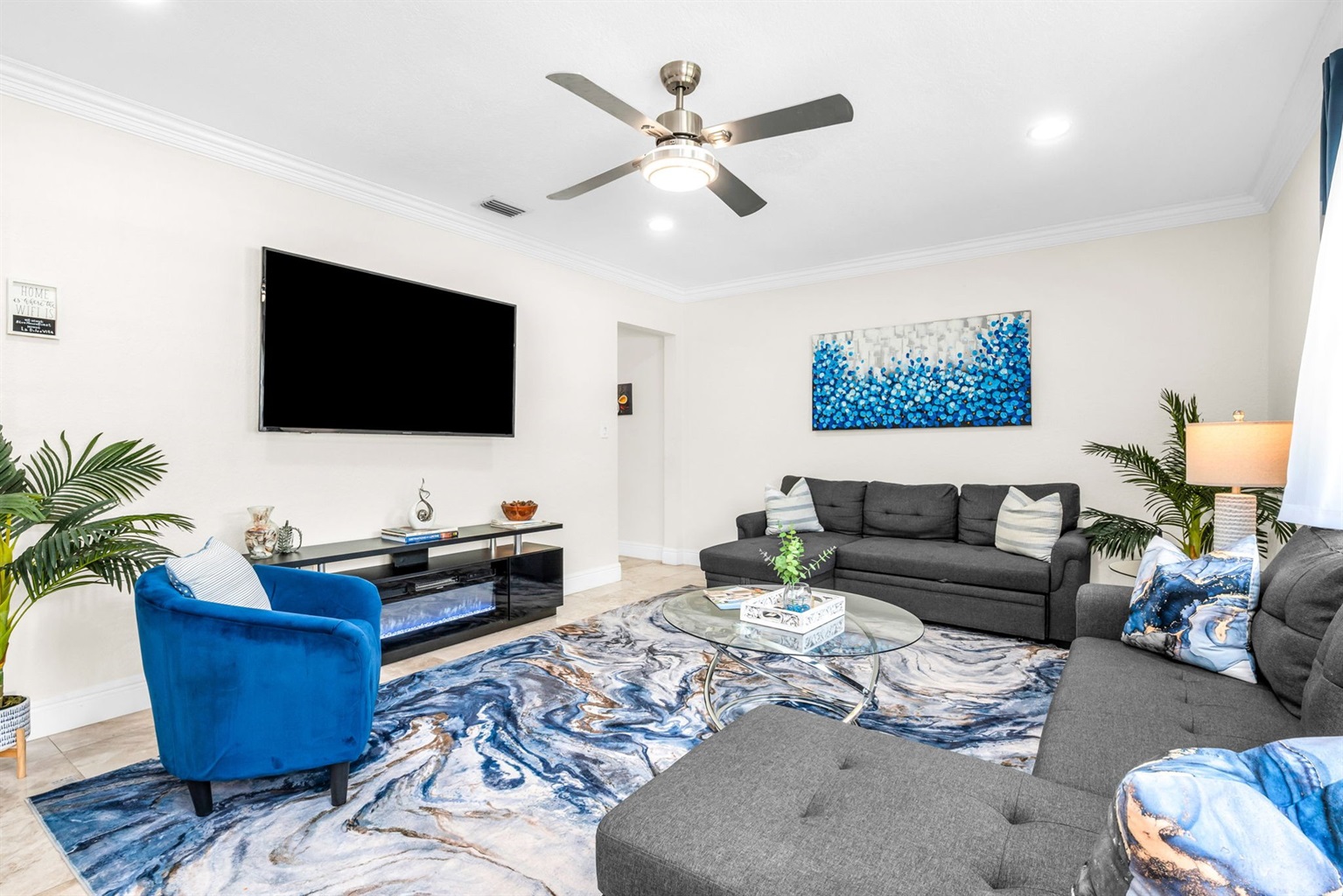 Large family-friendly living room with two queen pull-out sofas, flat-screen smart TV, and stylish coastal décor—great for groups needing extra sleeping options.