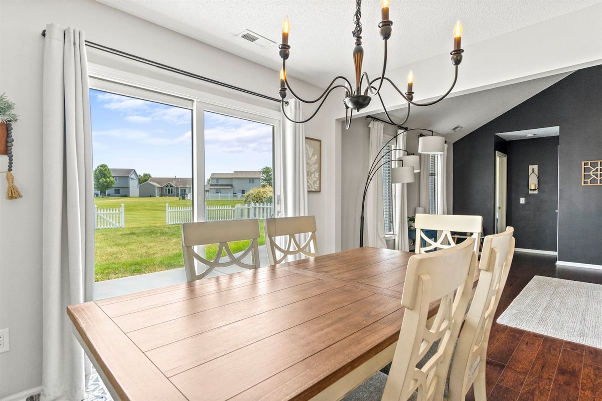 Dine with views of the private fenced yard and open green space, all visible through the large glass doors that invite sunshine into every meal.