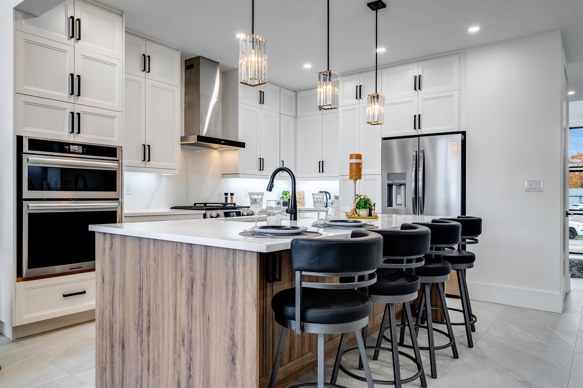 A chef's dream kitchen with extra large eat-in island and high-end appliances including gas stove and two ovens.