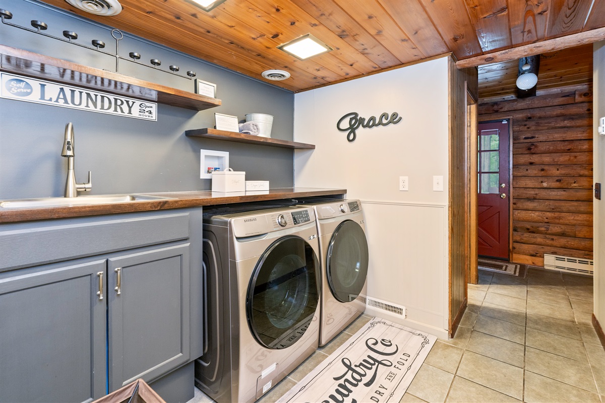 Updated laundry space with modern Samsung washer/dryer, farmhouse shelving, and deep sink for all your vacation needs.