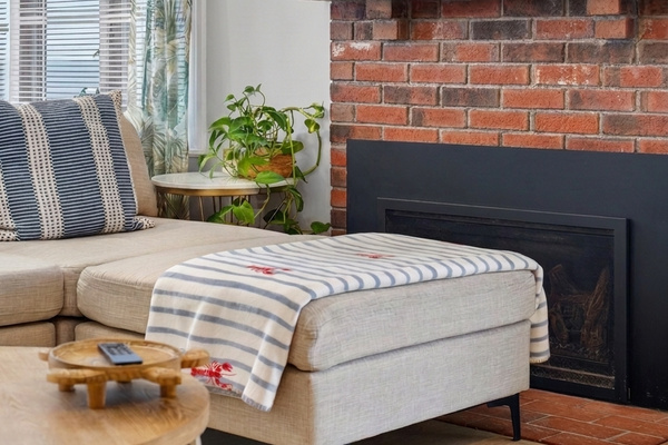 A cozy spot beside the brick fireplace, perfect for reading or relaxing after a day at the beach.