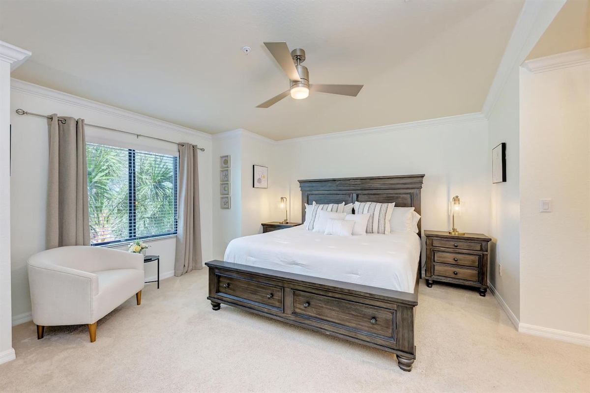 Wake up to serene views of the golf course and swaying palms from this spacious main bedroom. Featuring a king-size bed with two nightstands. A dresser provides good storage, and 40" TV. Nestled by the window, a reading chair invites you to unwind. 