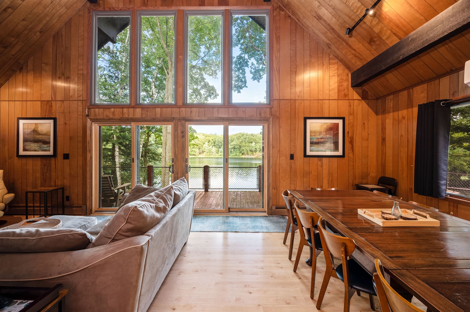 Living room with vaulted ceilings, wall of windows, and lake views