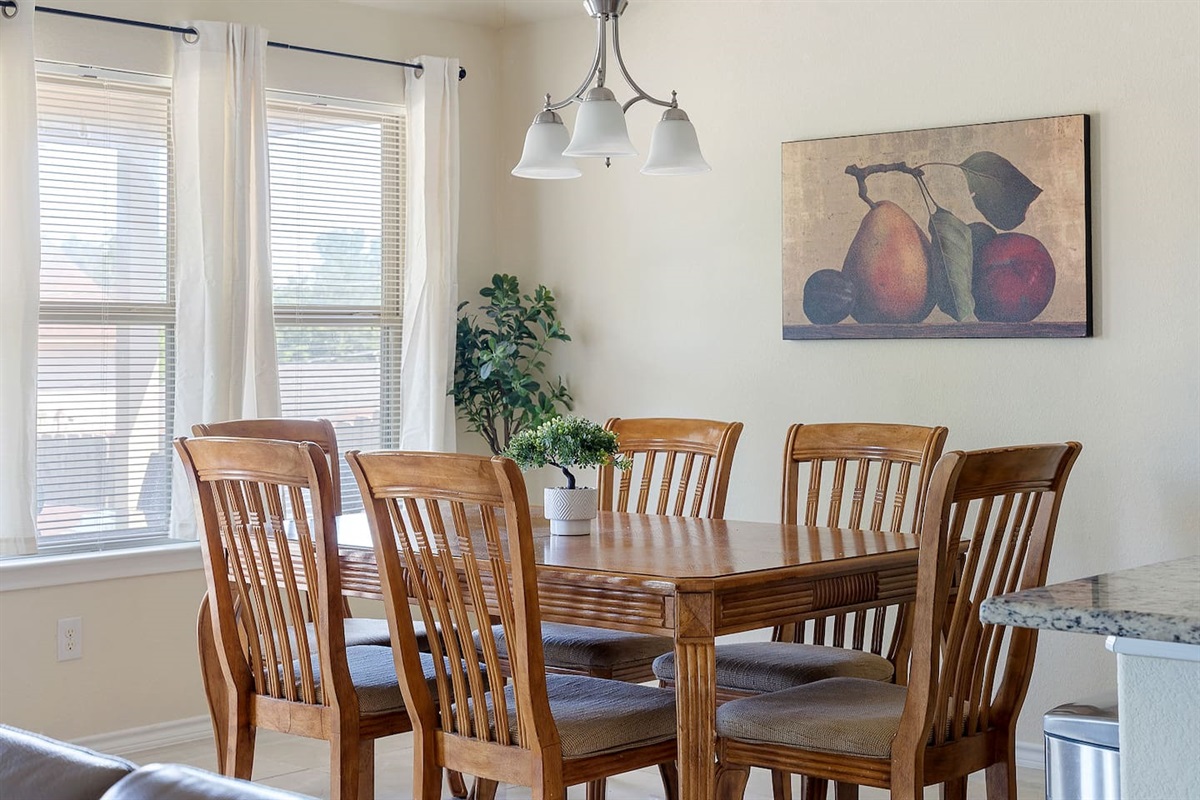 Enter a bright and inviting dining area with a classic wooden table set, enhanced by tasteful wall art and a stylish light fixture.