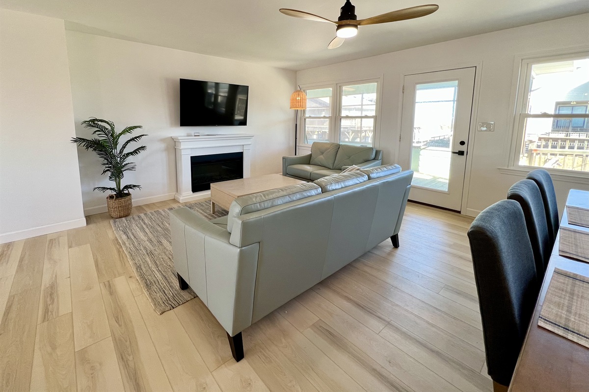 Large smart TV over electric fireplace with plenty of space on comfortable couches to watch