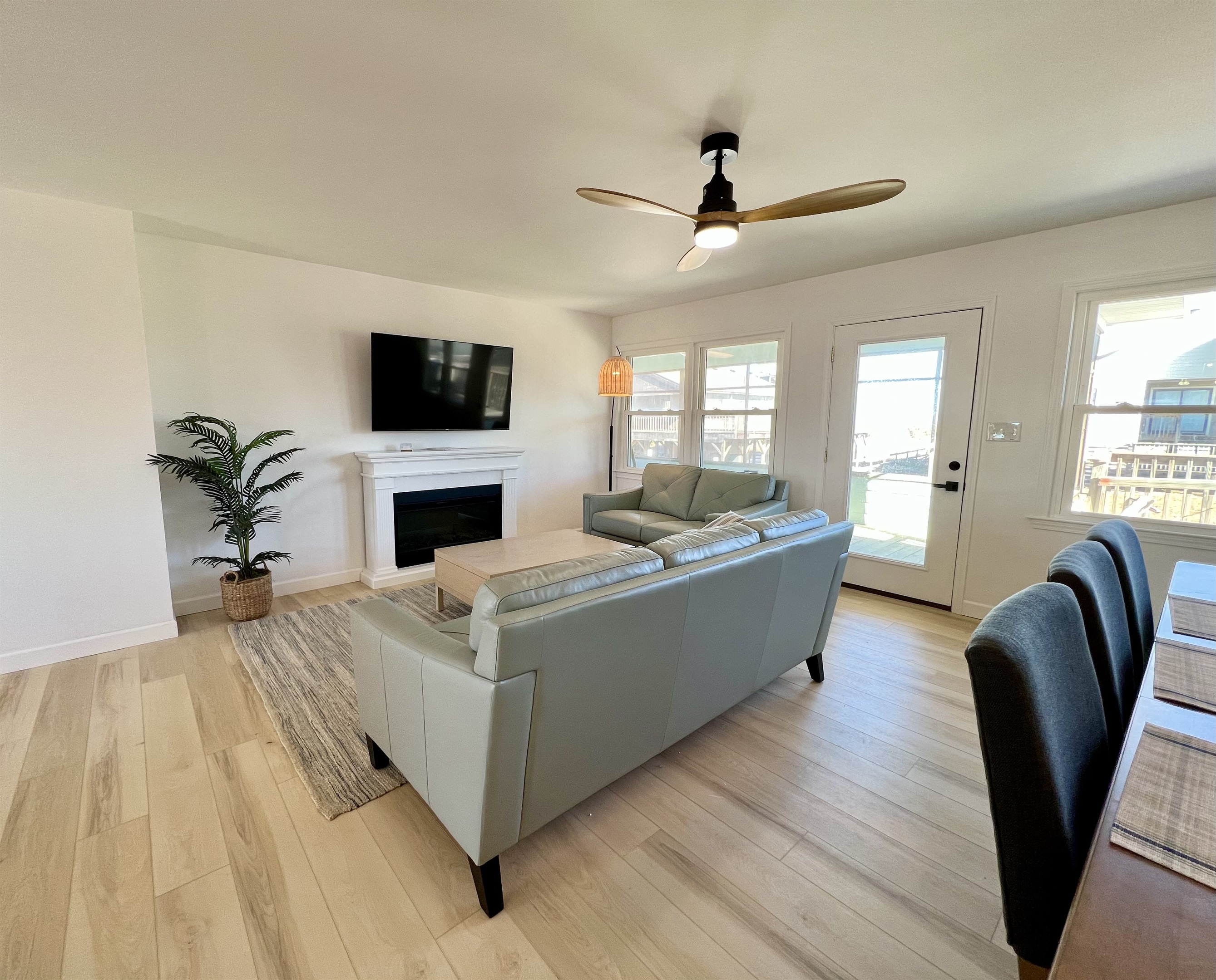 Large smart TV over electric fireplace with plenty of space on comfortable couches to watch