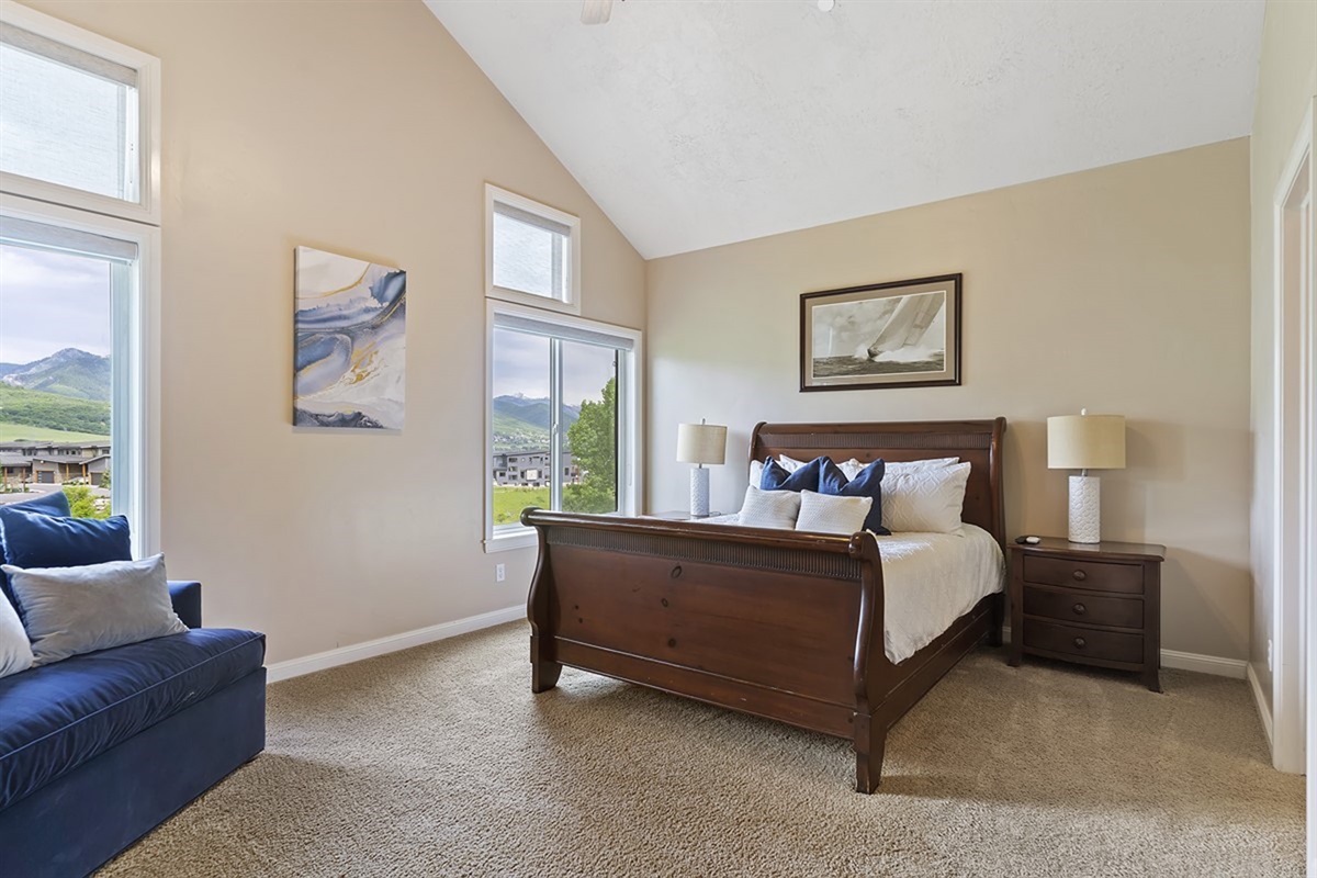 Serene primary bedroom with vaulted ceilings, natural light, and beautiful mountain views.