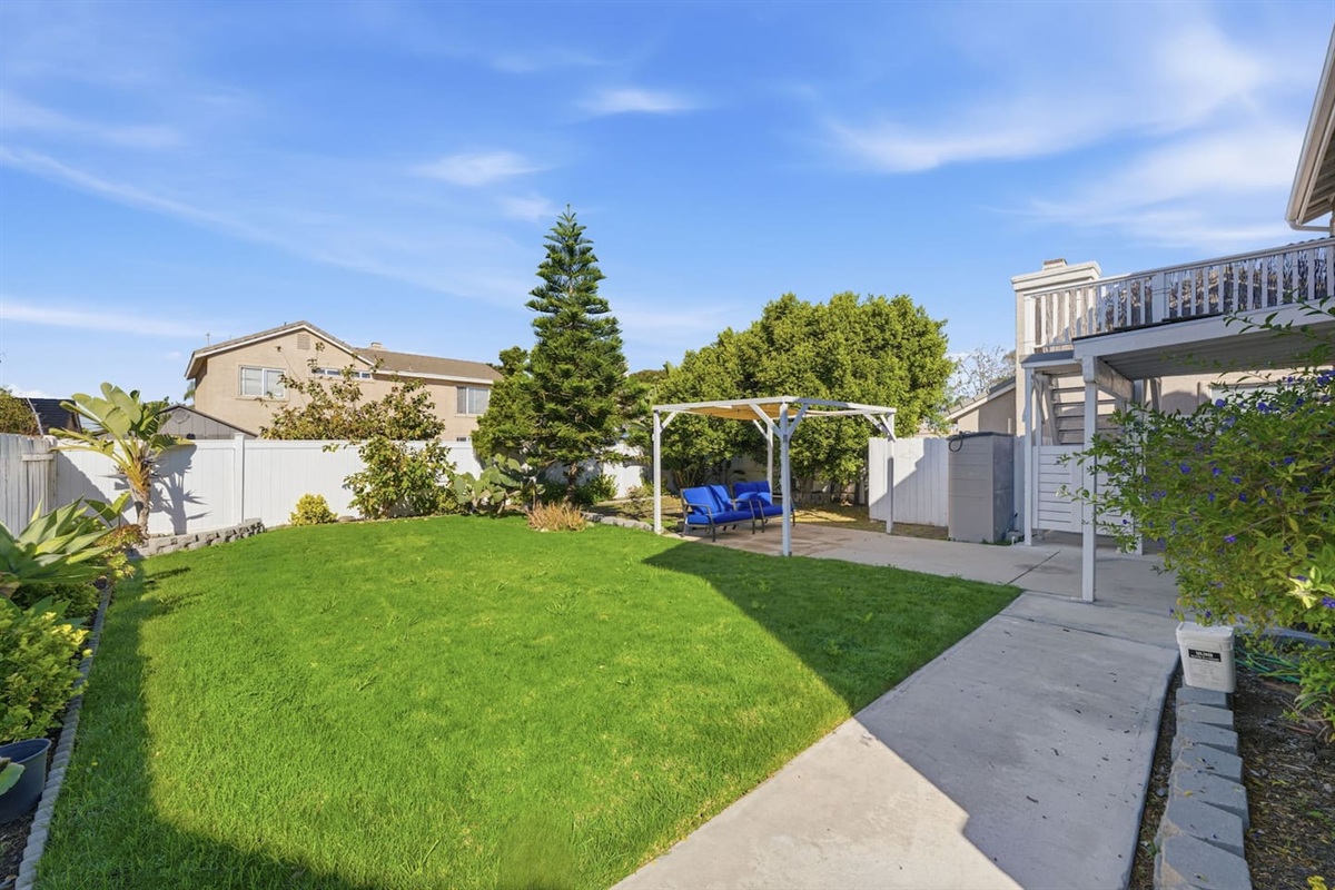 Fully fenced backyard with green lawn, pergola, and patio access. Private outdoor space for families and groups.