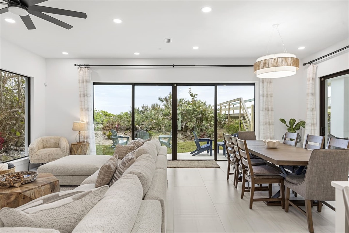 Open dining and living room with large glass windows and doors that seamlessly open to the backyard patio, perfect for indoor-outdoor living.