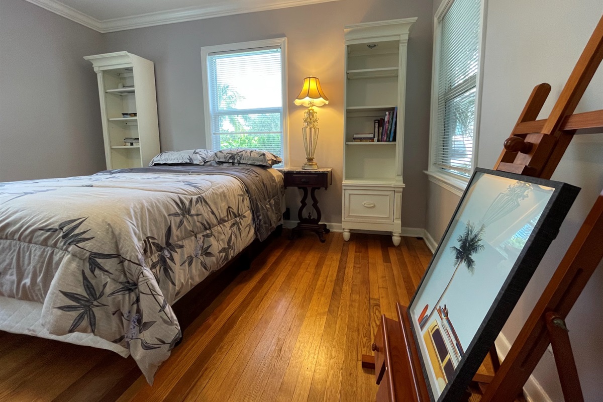 The second bedroom features a queen-zied bed and a stylish painter's floor stand.