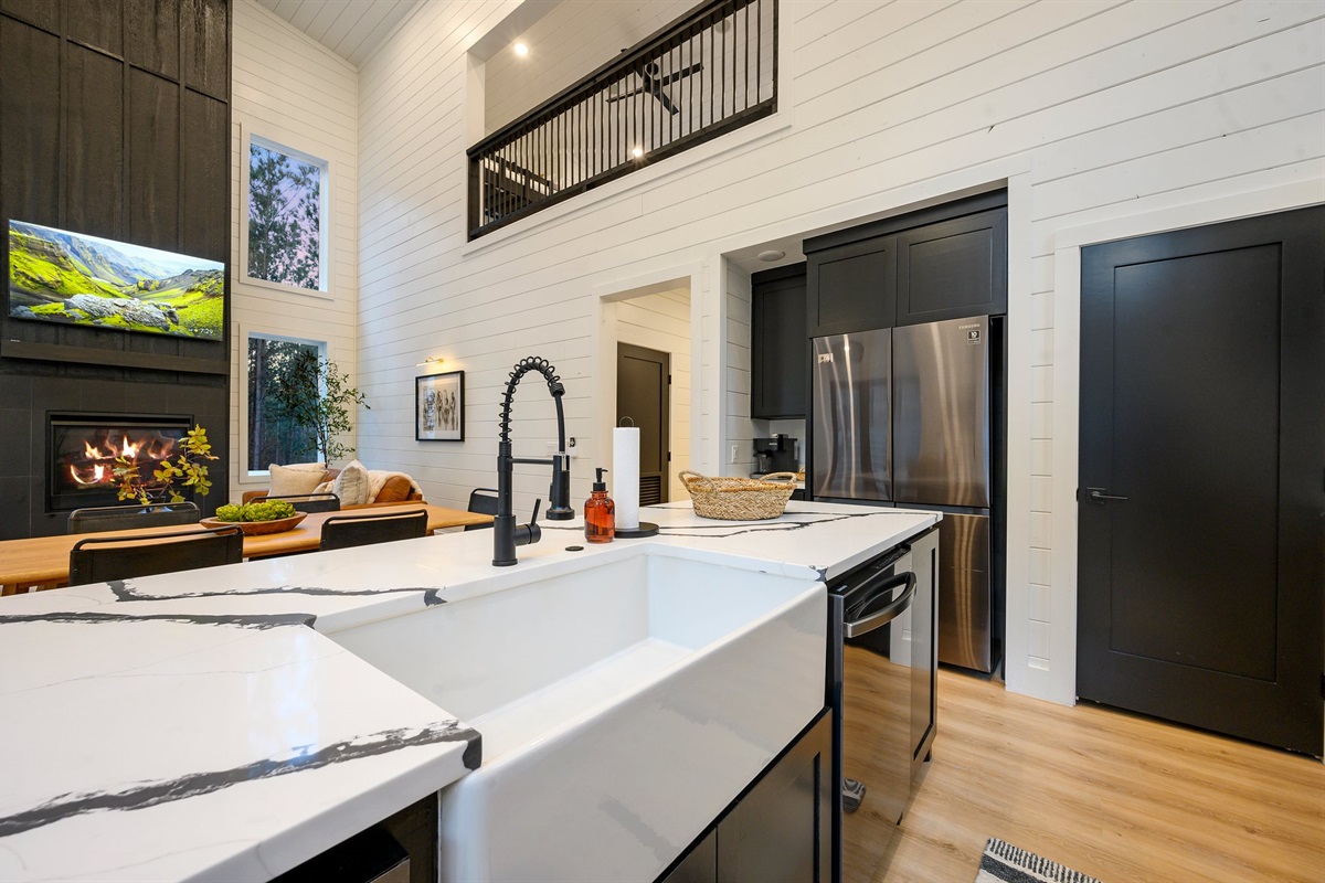 The modern farmhouse kitchen features sleek black cabinetry, warm wood accents, and stunning quartz countertops.