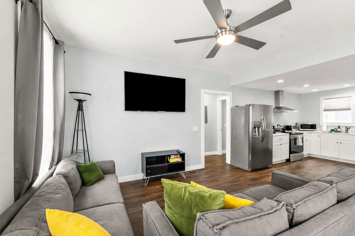 Comfort meets convenience in this inviting living room with a large TV, board games, and easy access to the kitchen and dining area.